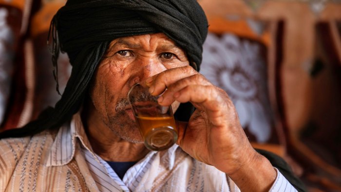 Portrait of an elder in a dark turban drinking tea from a glass